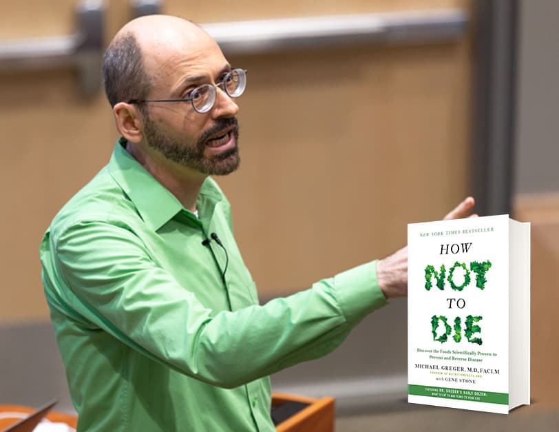 Dr. Greger in a green shirt gesturing towards audience